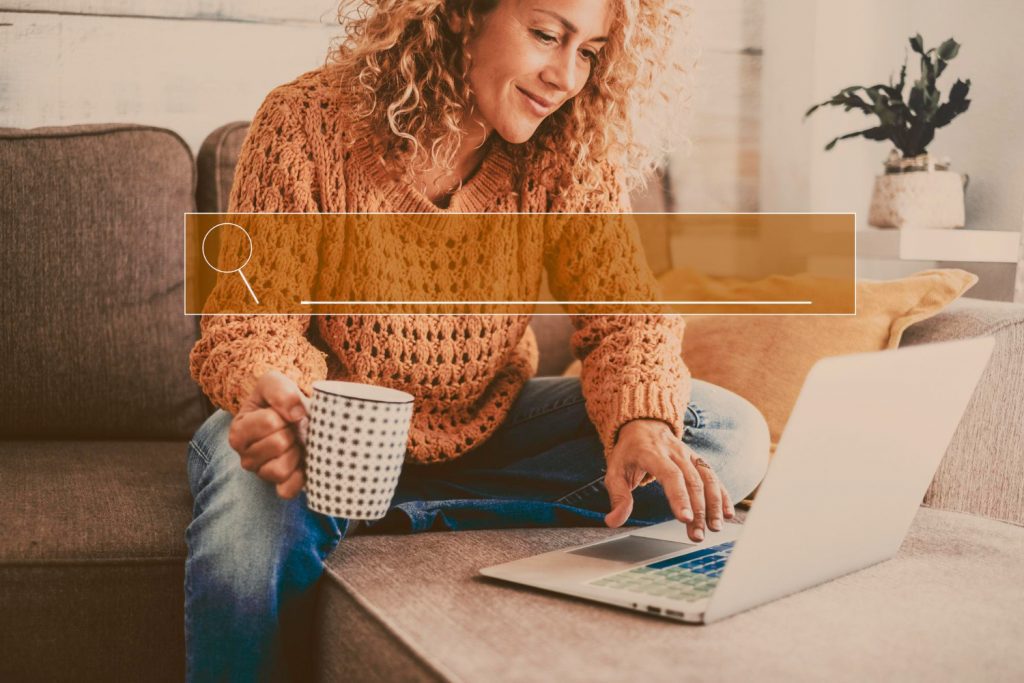 Agencia SEO en Madrid. Una mujer busca en internet desde su portatil en un salón.