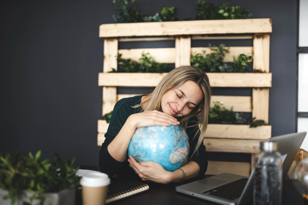 Cambio climático. Una mujer abraza una bola del mundo desde su oficina.